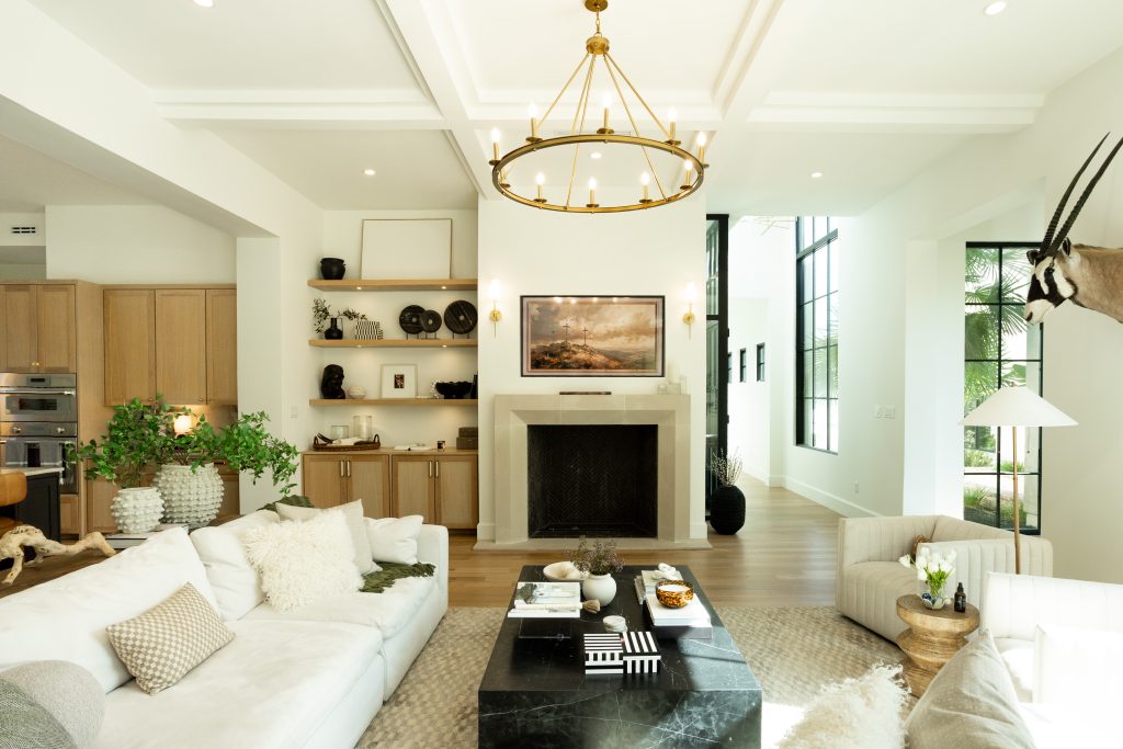Bright modern living room with white sofa, brass chandelier, and black marble coffee table