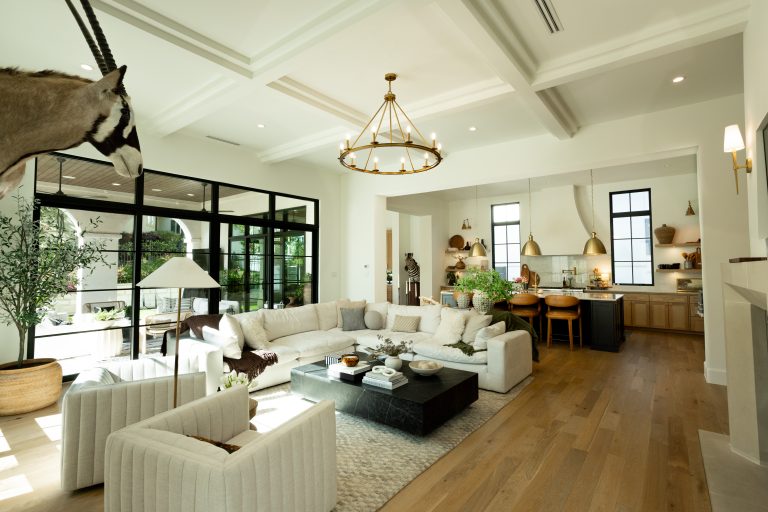Living area with a couch and pillows, objects on the coffee table and a zebra in the background. The patio doors and outside area are in view.